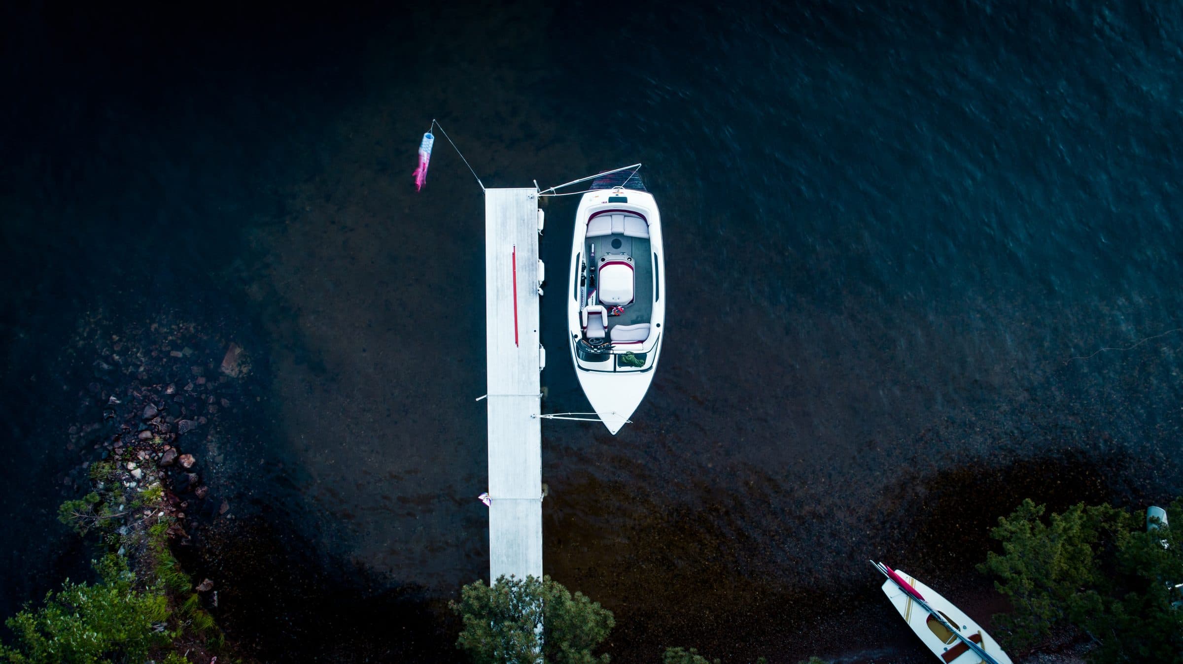 Top-down drone photo of a white bowrider at a private dock, the overhead angle used in boat listing photos