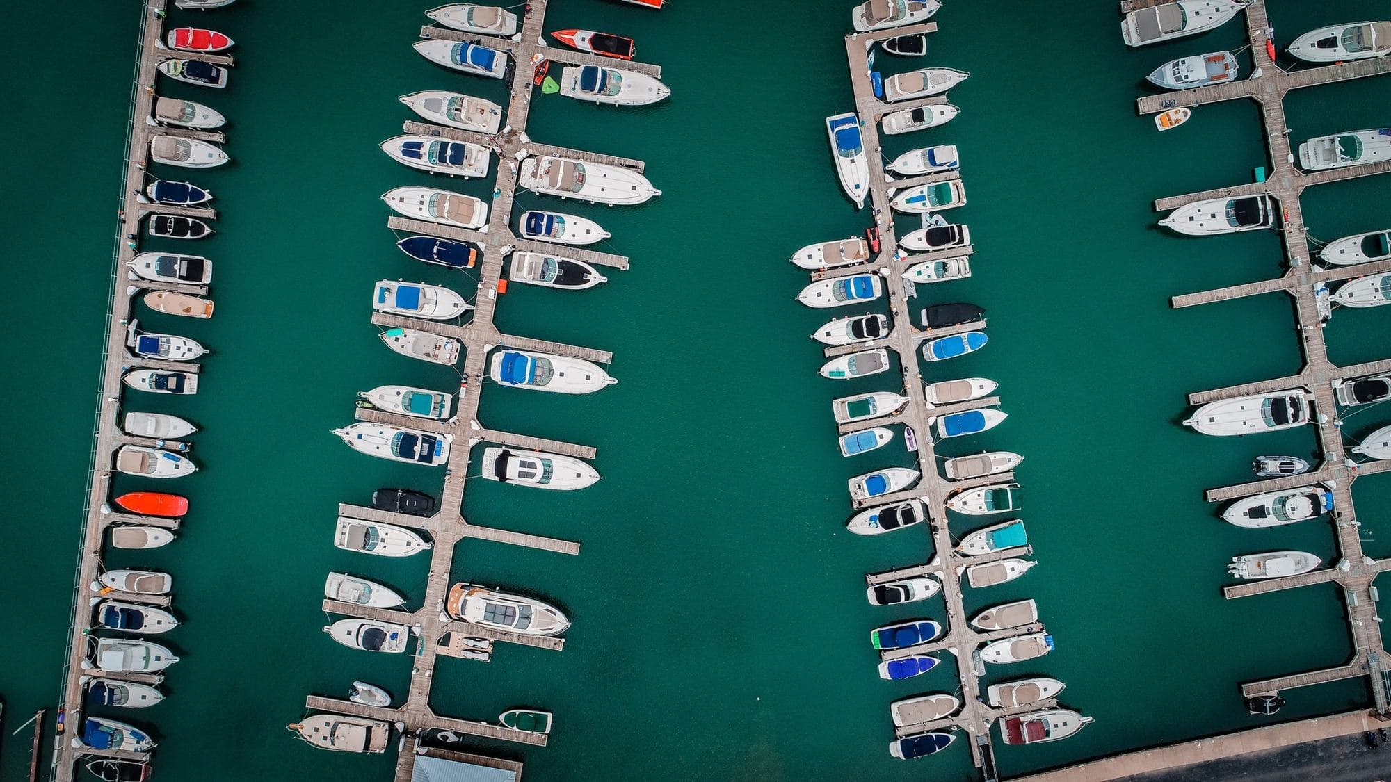 Overhead drone photo of a marina full of powerboats and cruisers tied along floating docks