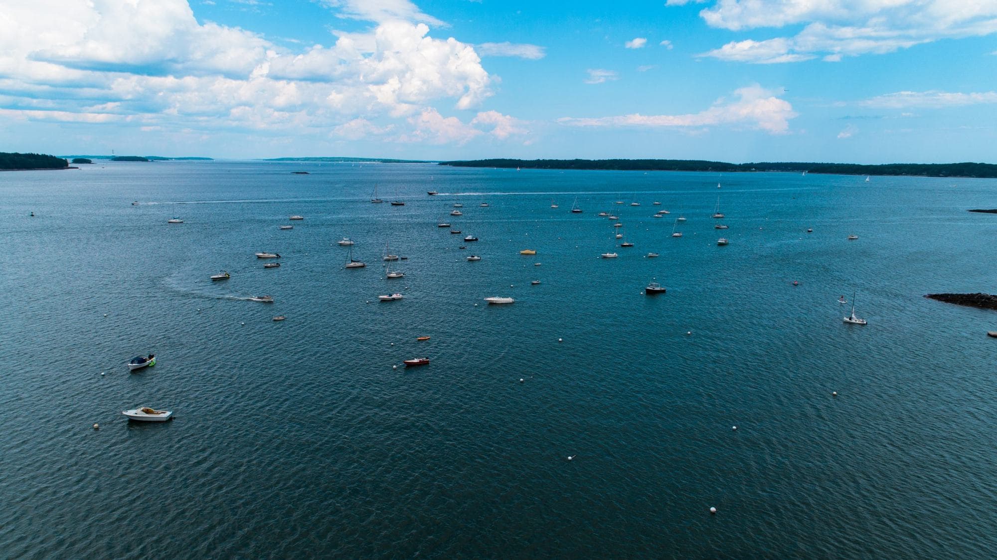 Wide aerial view of sailboats and powerboats anchored in a mooring field