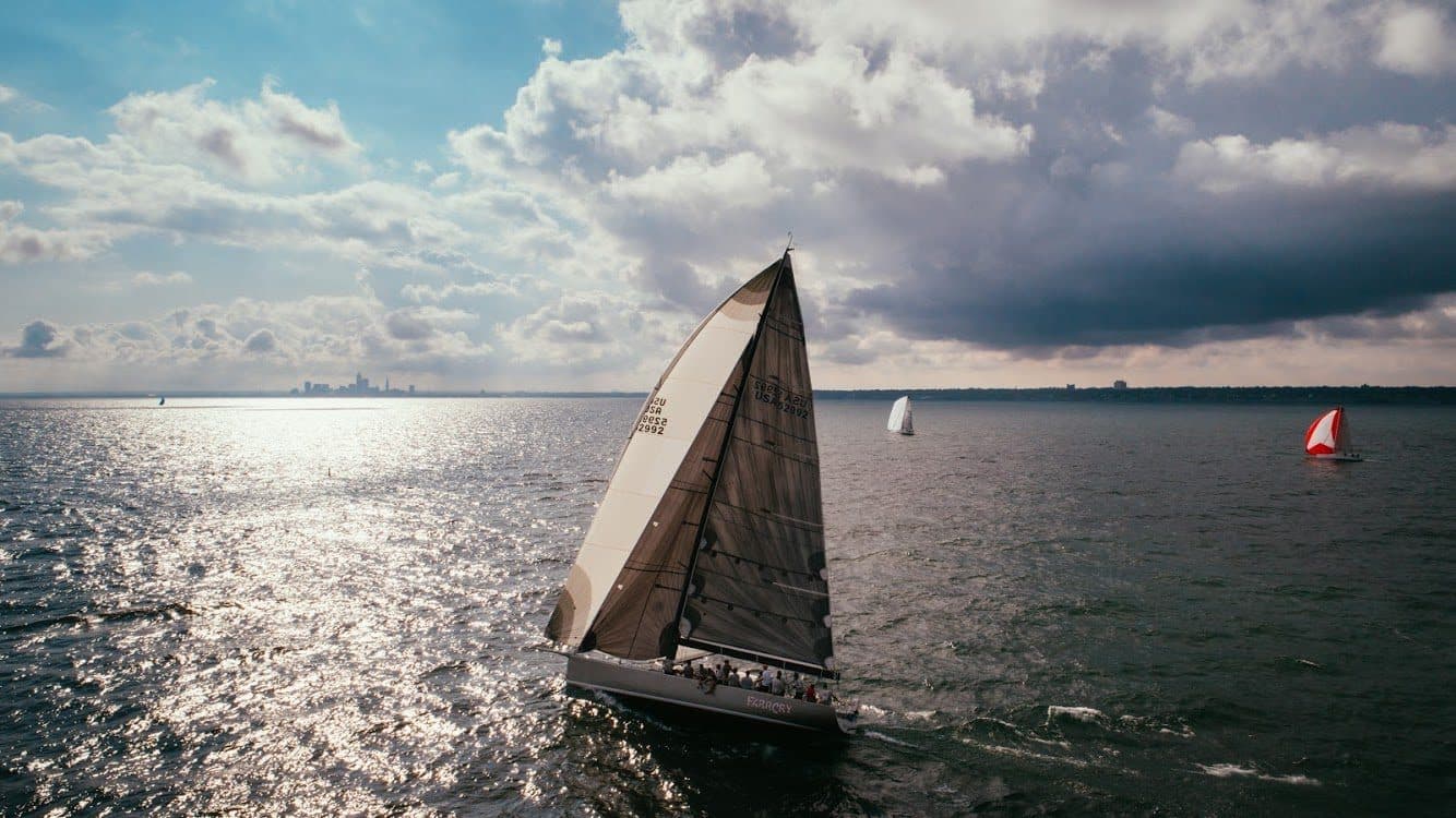 Aerial photo of a racing sailboat under full sail on Lake Erie off Cleveland, with another boat flying a red spinnaker behind