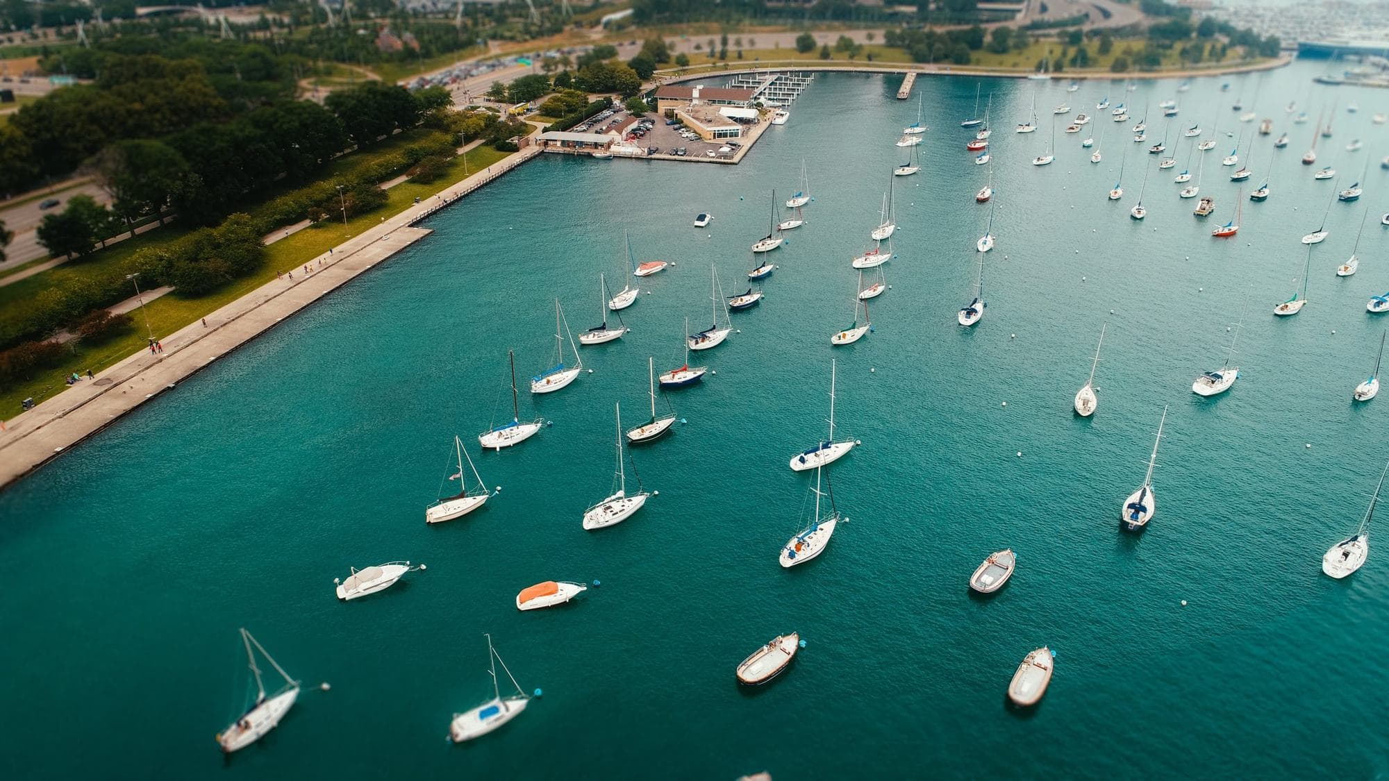 Drone photo of sailboats on moorings in a harbor beside a lakefront park