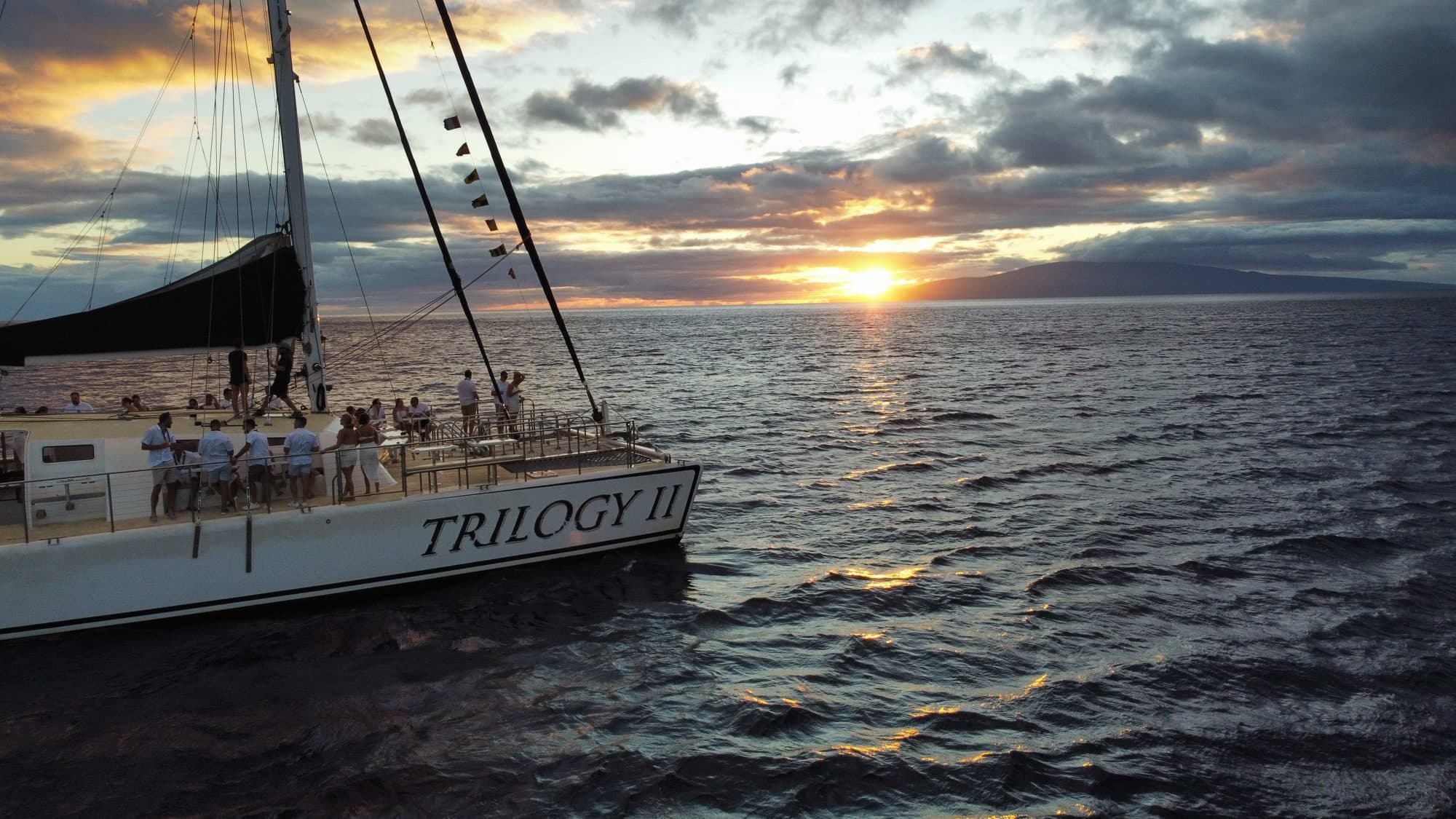 Aerial drone photo of a sailing catamaran with passengers at sunset