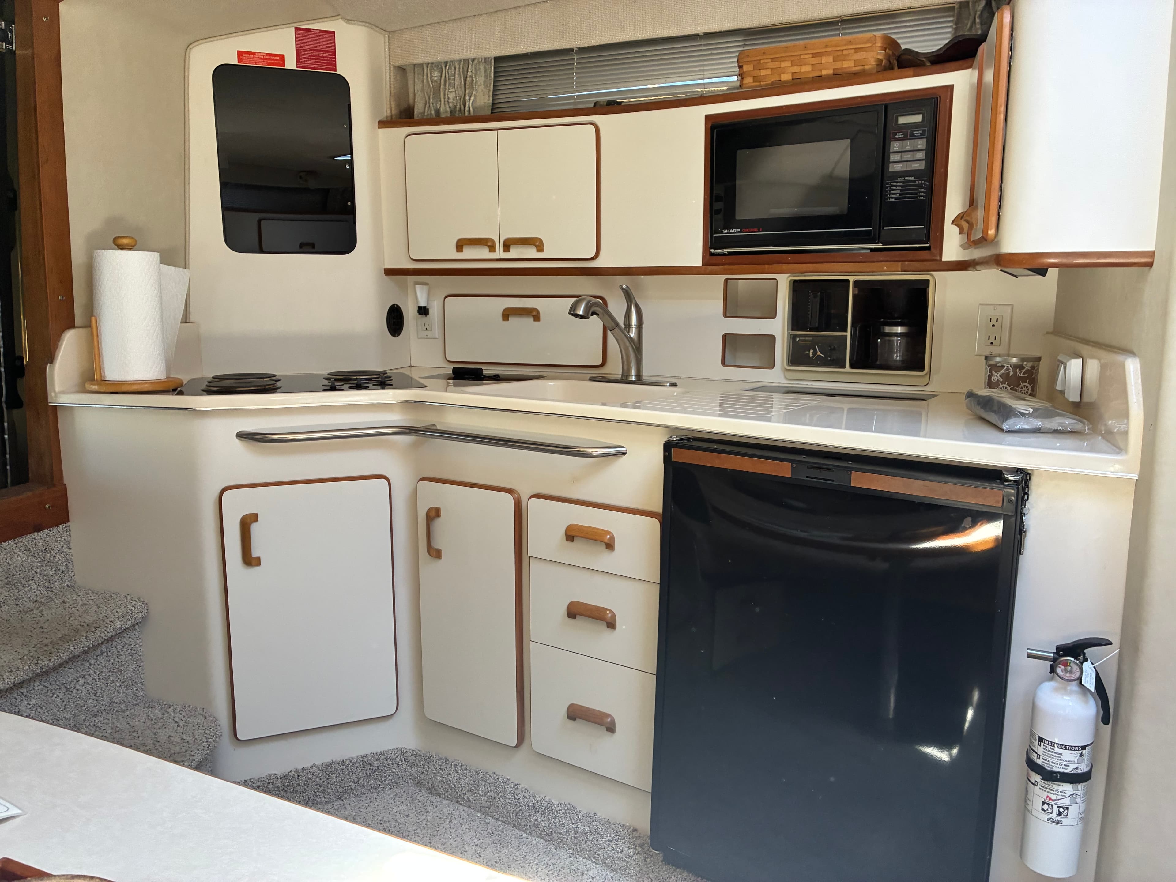 1990 Sea Ray 350 Express Cruiser galley with electric stovetop, sink, microwave, and refrigerator