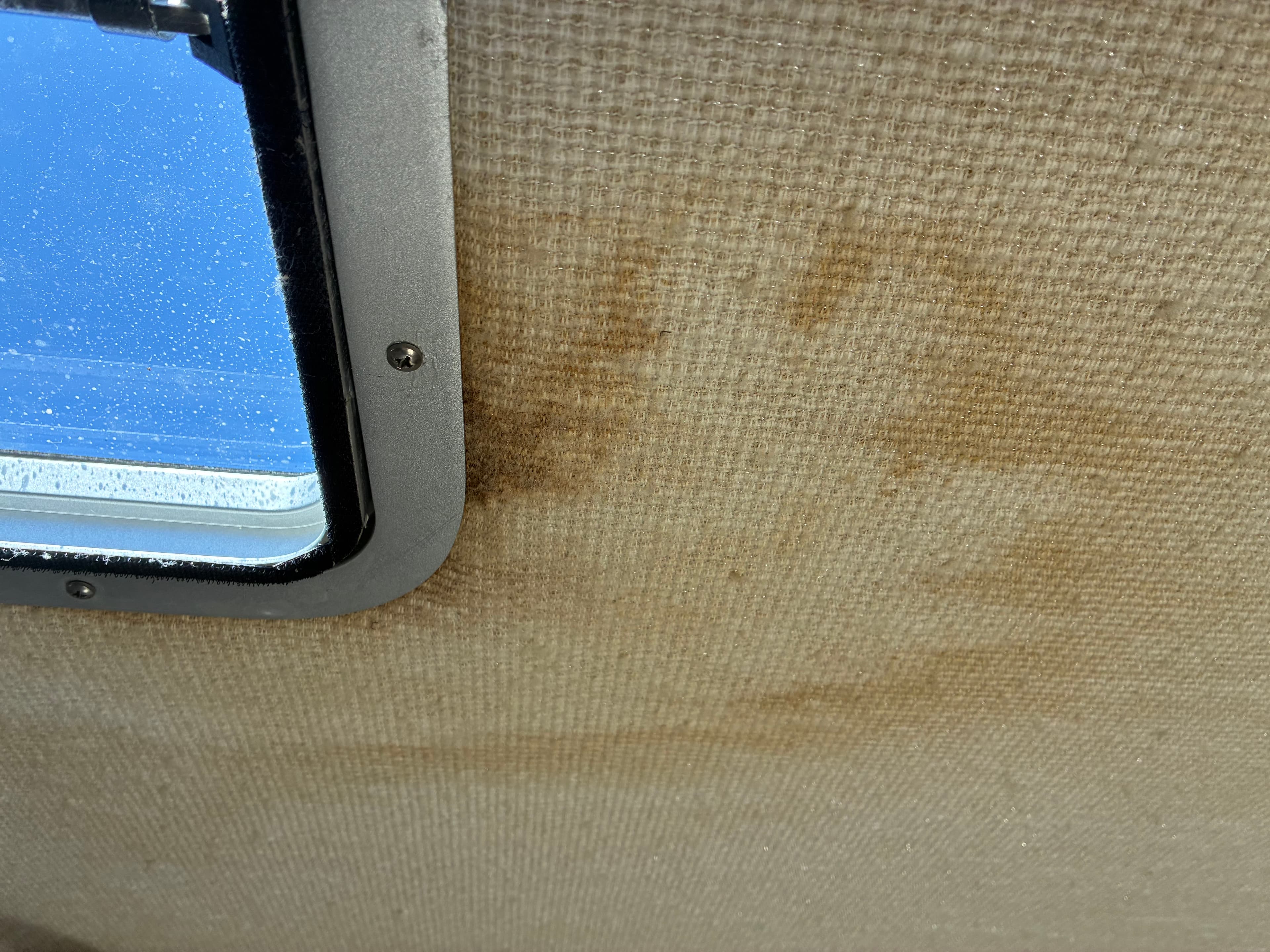 1990 Sea Ray 350 Express Cruiser cloth headliner showing minor staining near port window