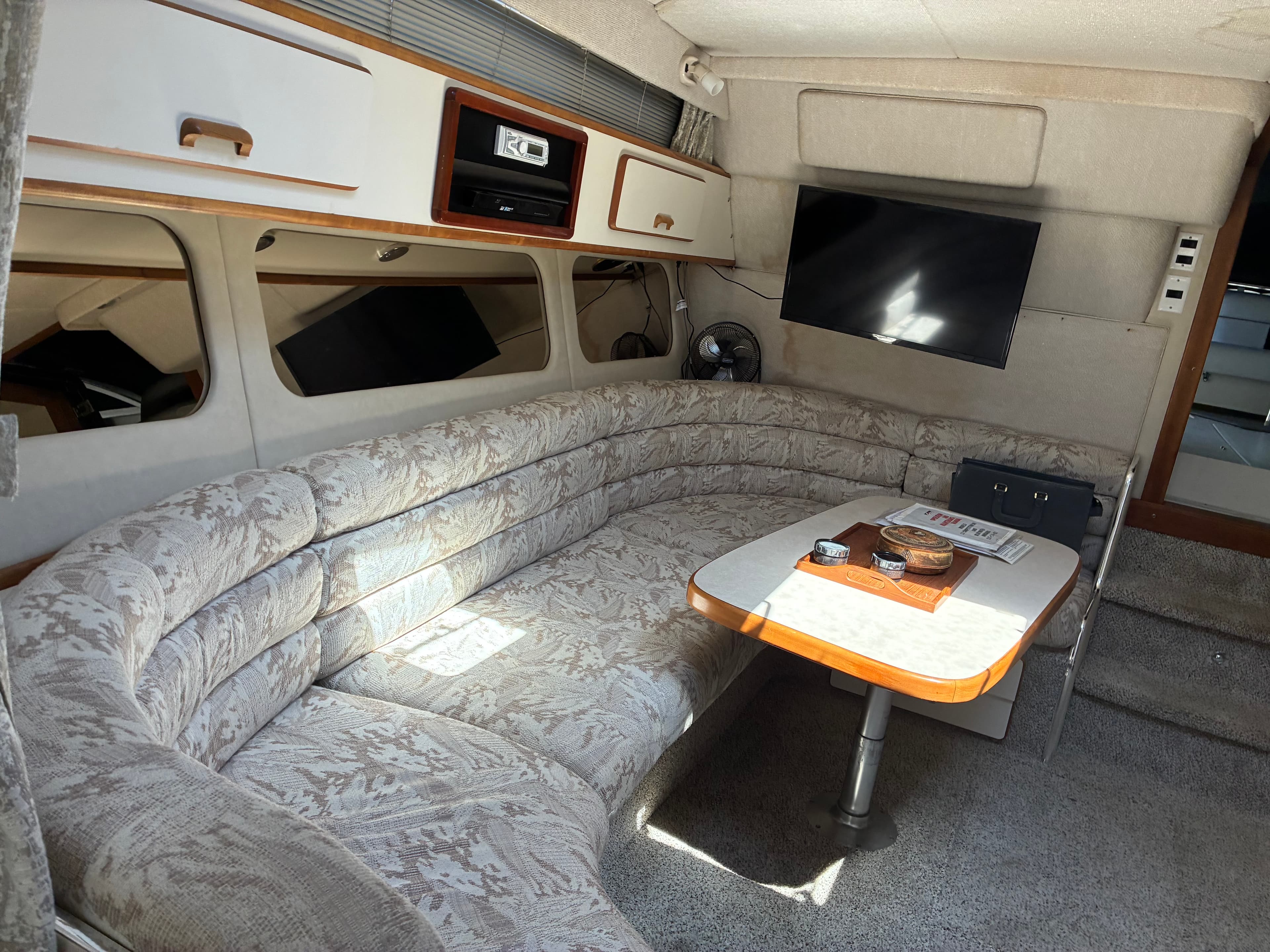 1990 Sea Ray 350 Express Cruiser salon with wraparound dinette and flat-screen TV