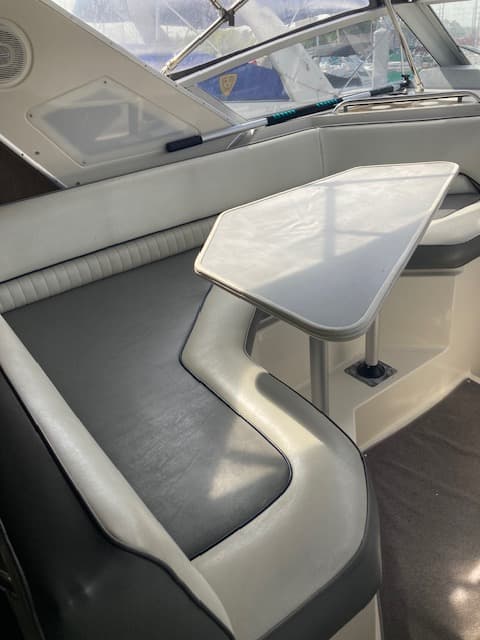 1994 Bayliner 3055 cockpit with dinette table and curved bench seating under bimini